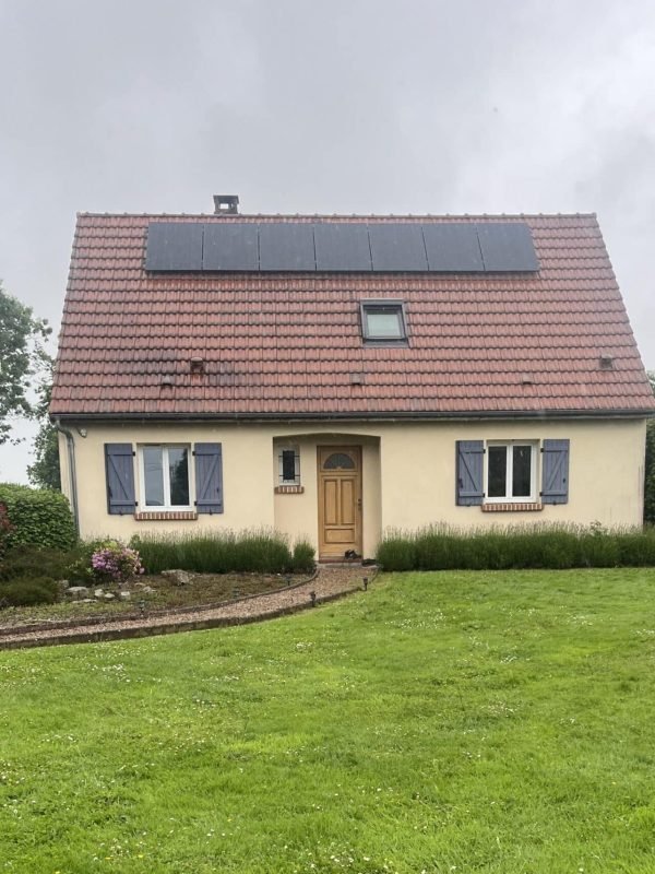 Maison individuelle avec jardin, équipée de panneaux solaires sur le toit, dans un environnement verdoyant