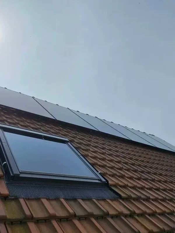 Vue du toit d'une maison avec une installation complète de panneaux solaires sous un ciel ensoleillé.