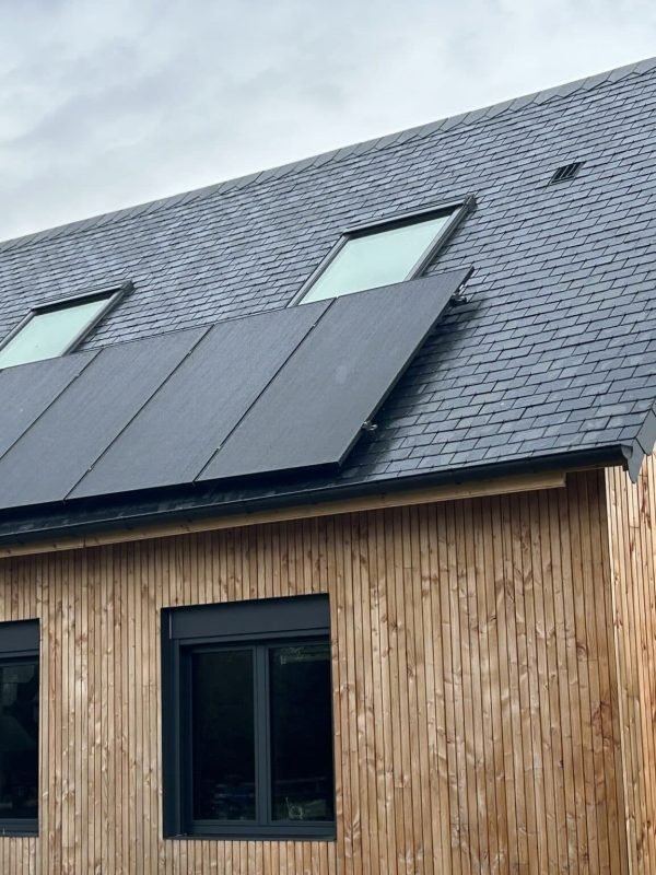 Vue sur un toit en bois moderne avec plusieurs fenêtres de toit et panneaux solaires intégrés.