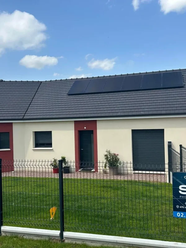 Maison équipée de panneaux solaires noirs par Sileos, panneau de chantier devant la clôture